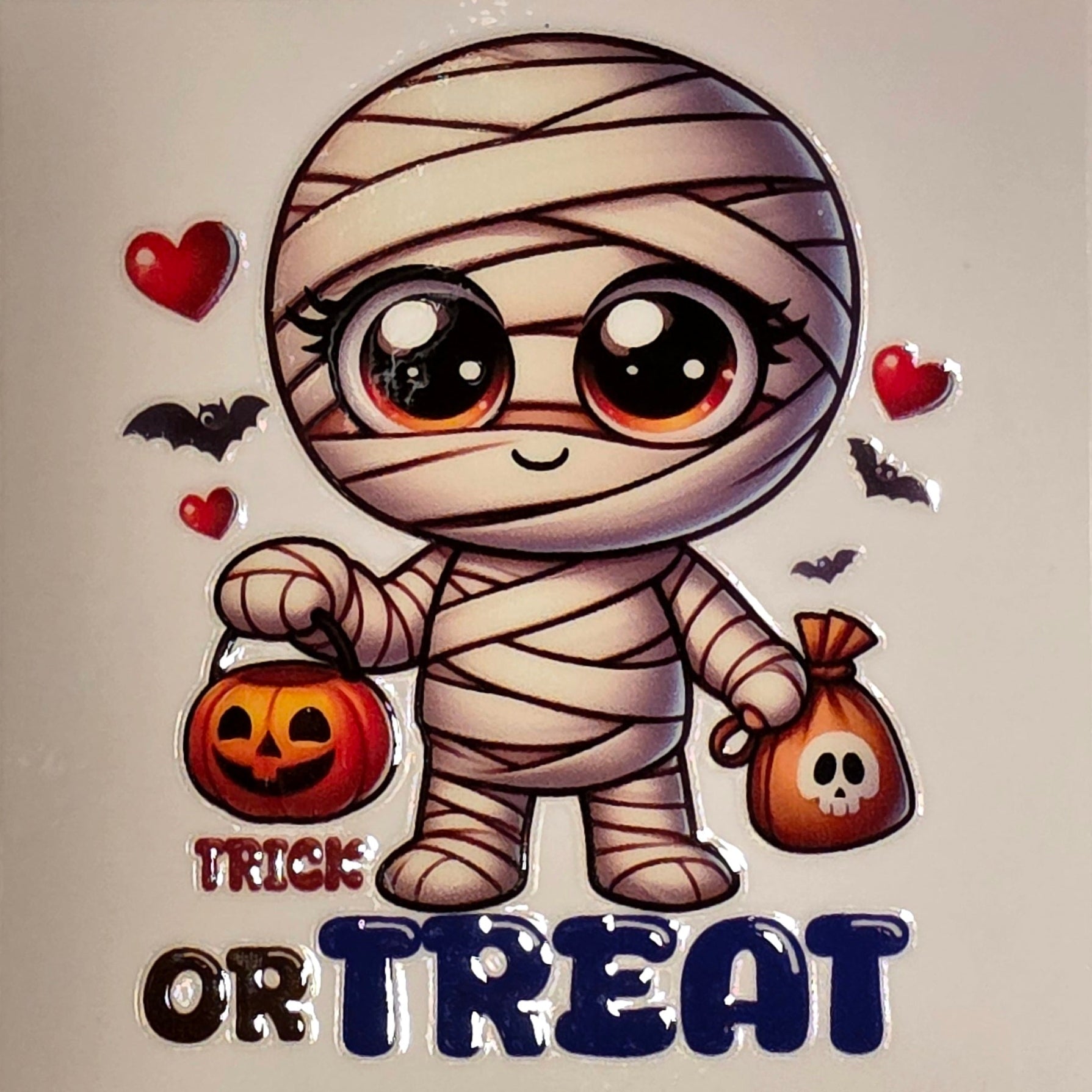 Cartoon mummy holding a pumpkin and a bag with 'Trick or Treat' text on a beige background.