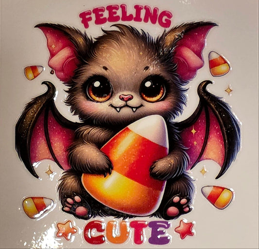 Cartoon bat holding a candy corn with 'Feeling Cute' text on a marble background